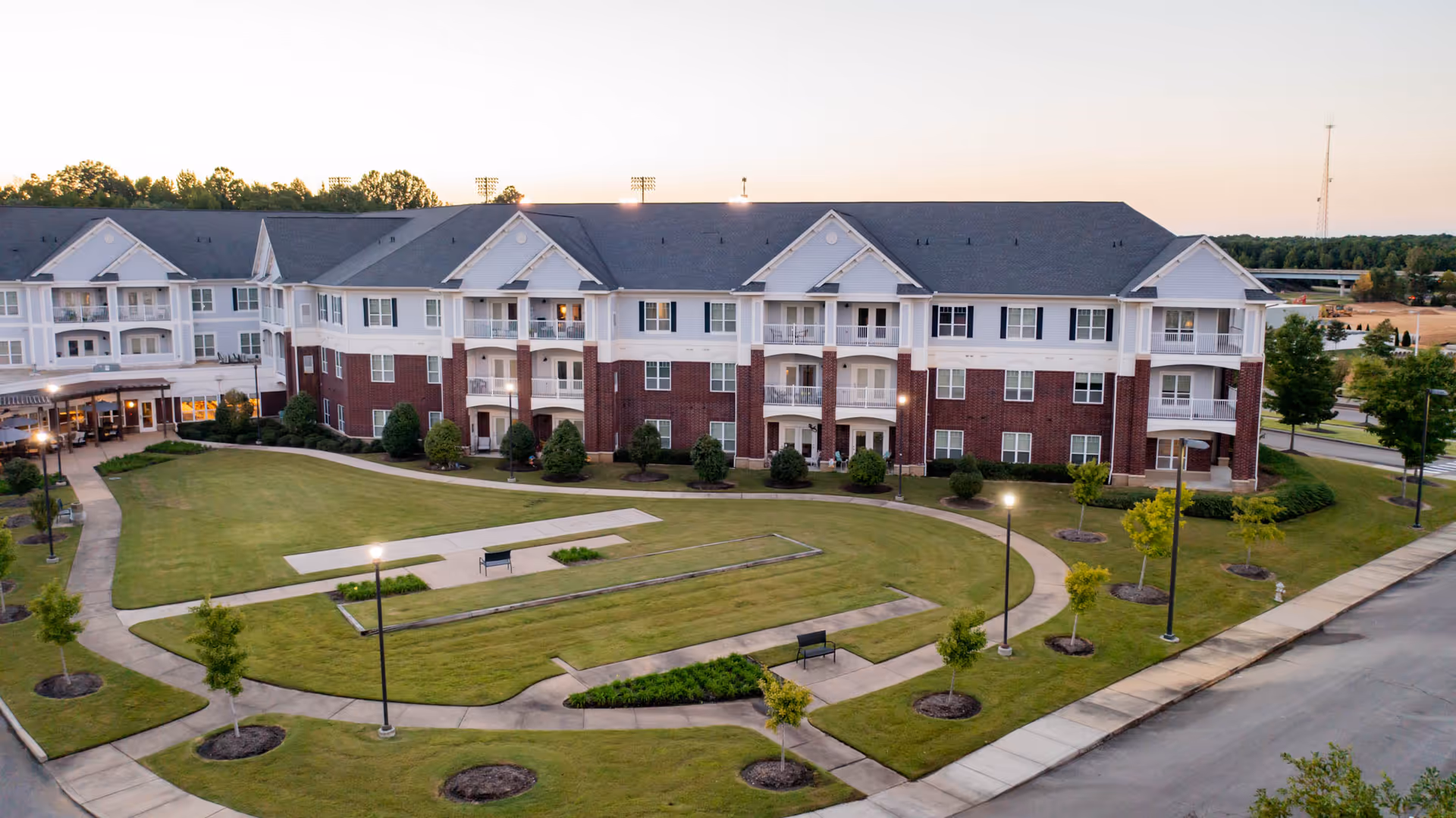 Exterior view of Irene Woods Assisted Living: brick and white building with landscaped courtyard and benches.