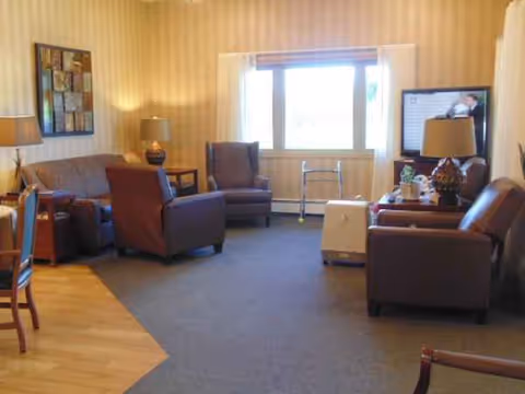 A cozy lounge area with multiple armchairs, a sofa, lamps, and a television.