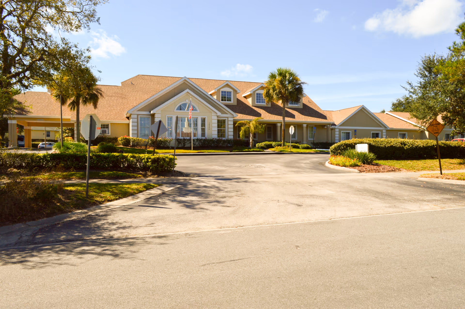 Front exterior of The Opal at Spring Hill with driveway and palm trees.
