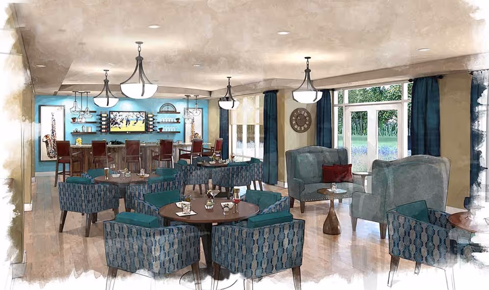 Bright communal lounge and dining area with round tables, patterned armchairs, a bar with stools, and large windows.