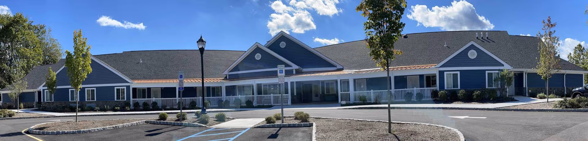 Graceland Gardens Assisted Living front exterior: single-story blue building with entrance and parking.