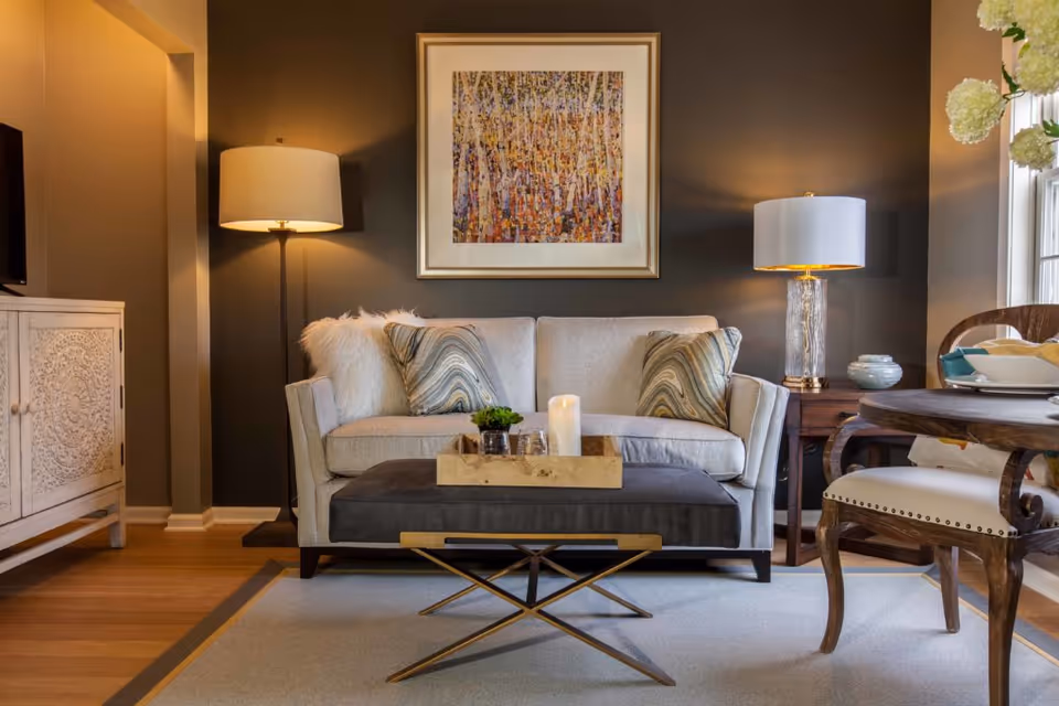 Stylish living room with a sofa, ottoman coffee table, lamps, and framed artwork.