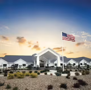 A senior living facility named Briarfield Place with a flag in the foreground under a sunset sky.