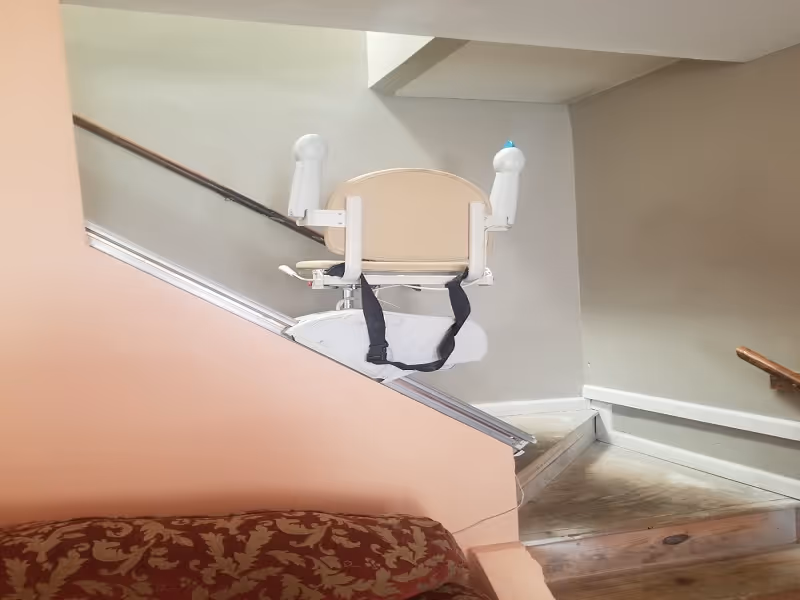 Stairlift chair mounted on a rail inside a home's stairway.