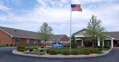 Exterior view of Mill Pond Health Campus with American flag, front entrance, and trimmed landscaping.
