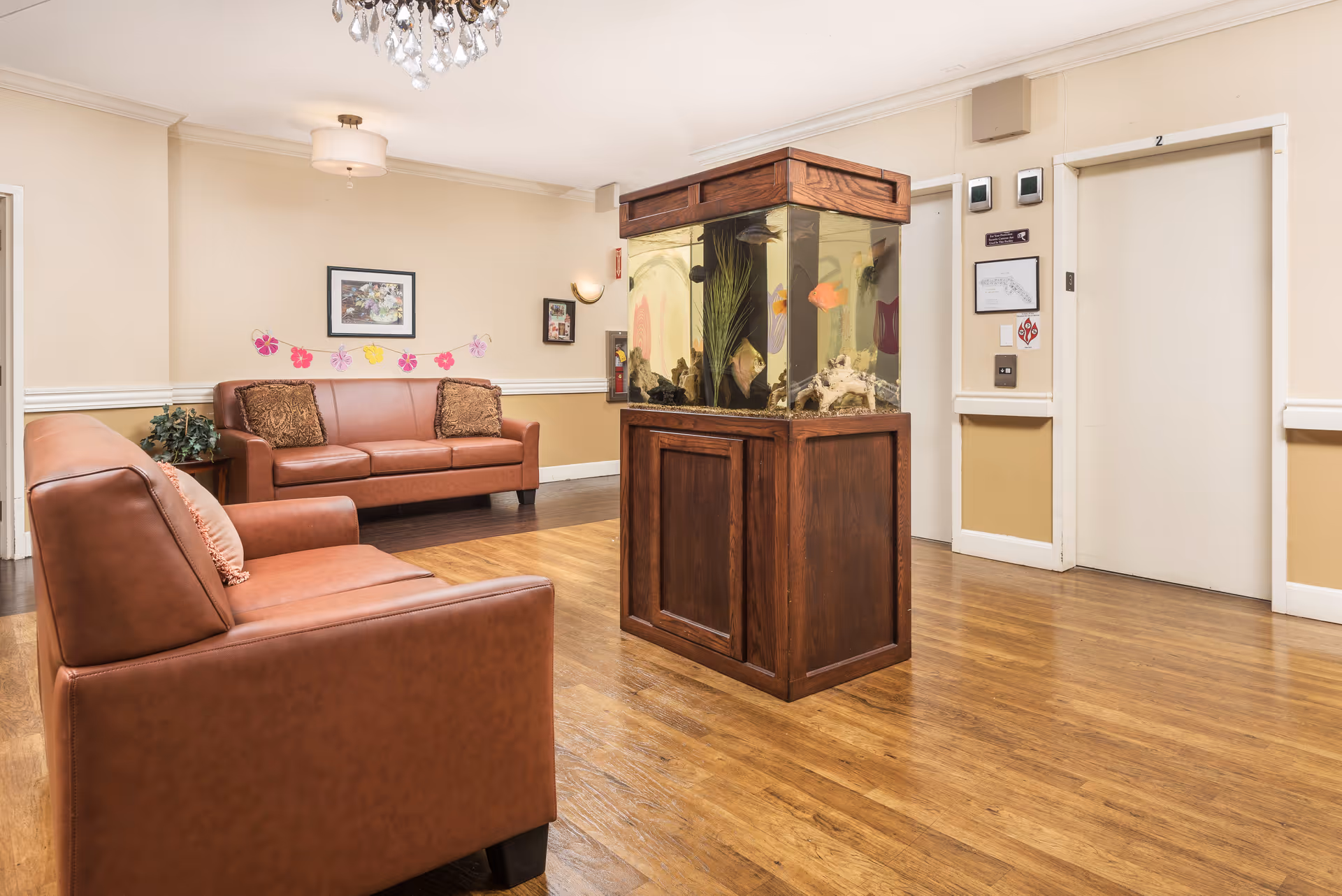 Lobby-style sitting area with leather sofas, a central aquarium, and elevators in the background.