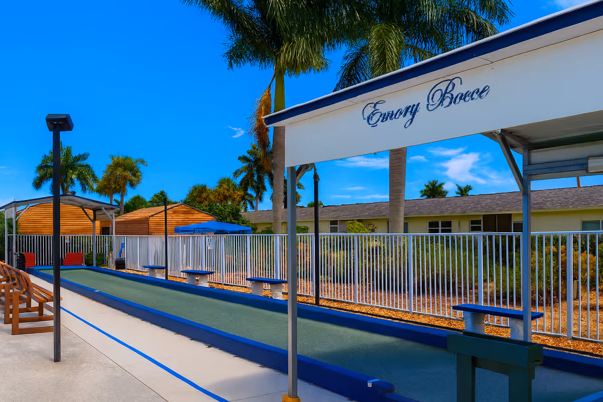 Outdoor bocce court area with covered seating, palm trees, and a sign reading 'Emory Bocce'.