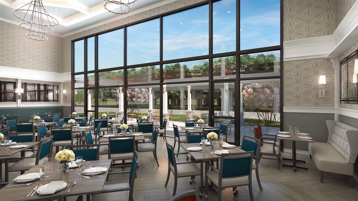Spacious dining room with multiple set tables and teal chairs and large floor-to-ceiling windows looking out to a patio and garden.