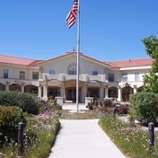 Front exterior view of The Village at Alameda with flagpole and landscaped entrance.