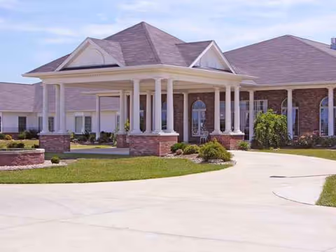 Exterior view of a Charter Senior Living facility with brick walls, columns, and a curved driveway.