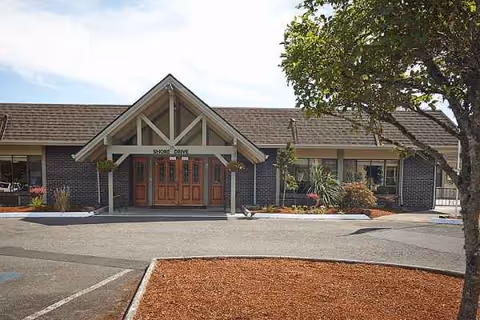 Meadow Park Care entrance features double wooden doors, brick facade, and landscaped front parking area.