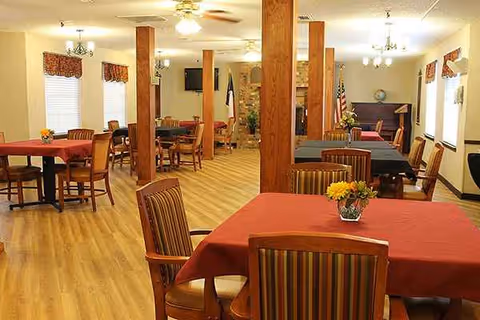 A spacious dining room with red tablecloths and wooden columns.