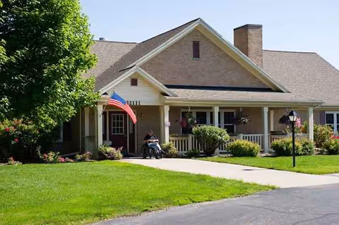 Front view of a senior living facility with a covered entrance and green lawn.