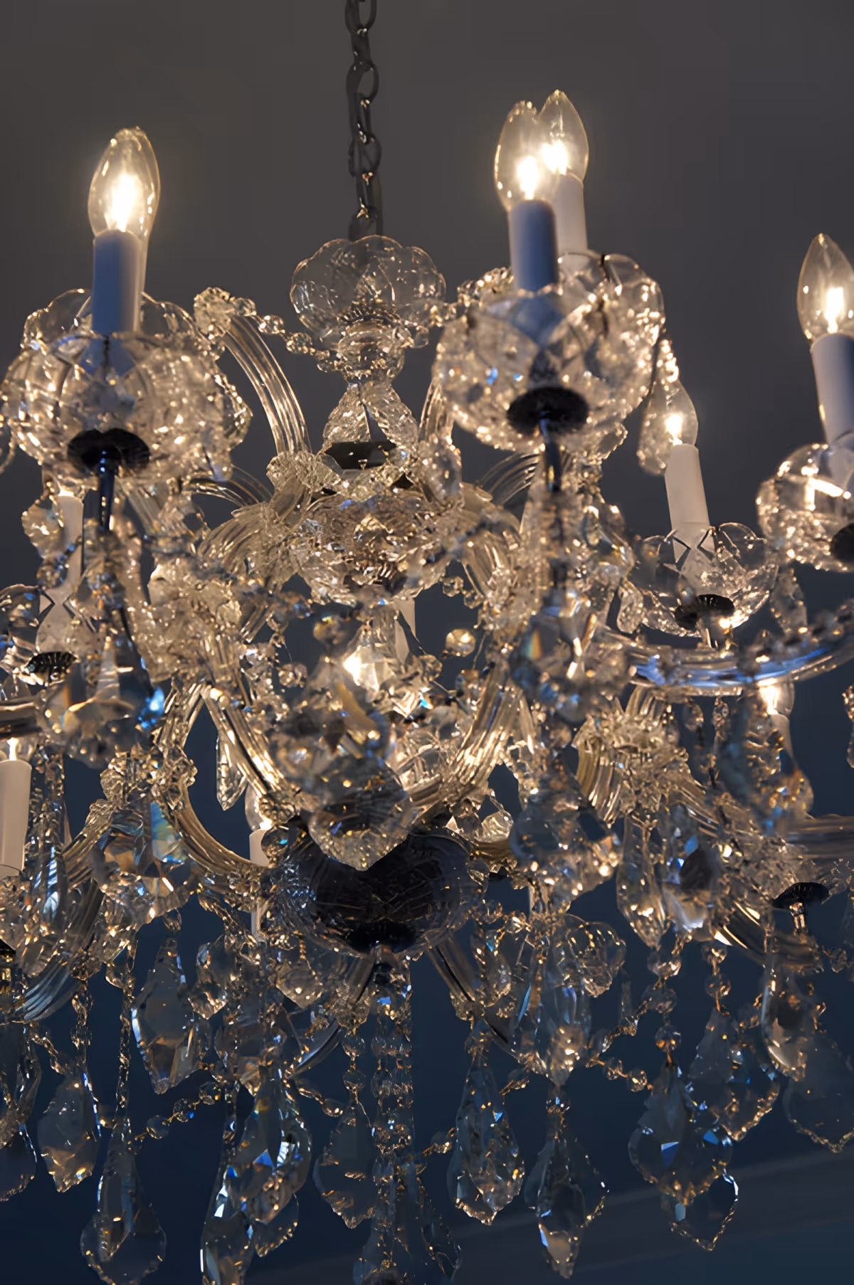 Close-up of an ornate crystal chandelier with multiple lit bulbs and hanging prisms.