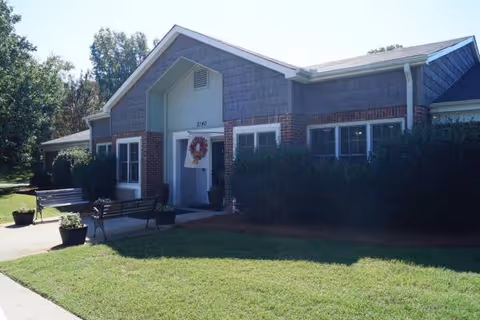 Front view of Willow Ridge Memory Care building with wreath on door and benches.