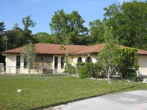 Exterior of Olive Branch facility: single-story building with brown roof, stone accents, and surrounding trees.