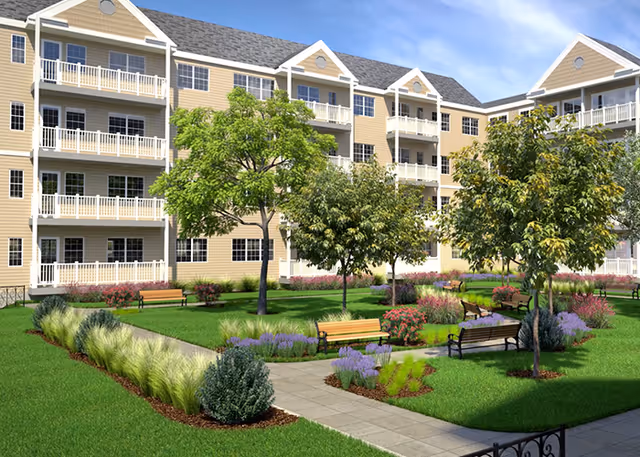 Landscaped courtyard with benches, trees, and walkways in front of a multi-story building with balconies.