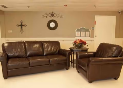 Brown leather sofas and a side table with flowers in a small lobby lounge.