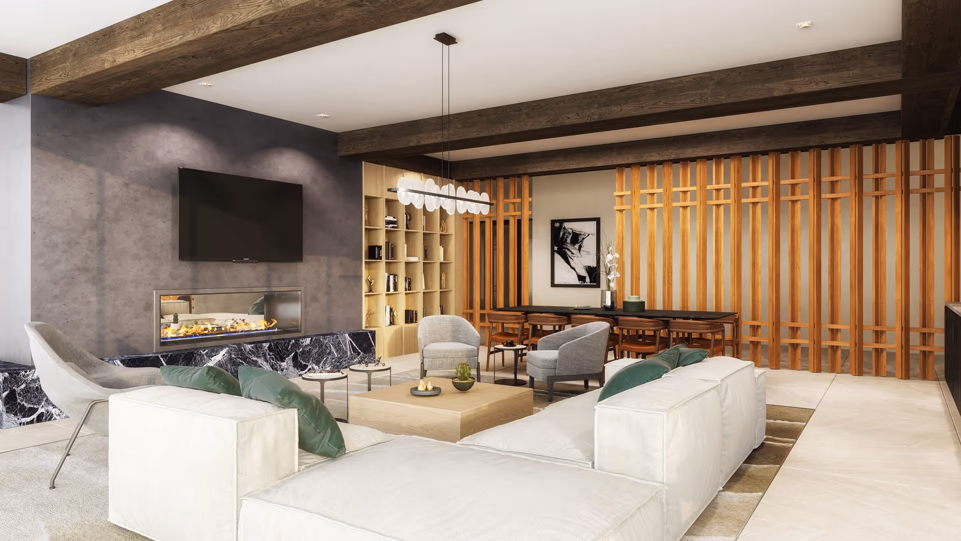 Modern living room with a large white sectional sofa adorned with green pillows, two gray armchairs, a light wooden coffee table with decorative items, a wall-mounted flat screen TV above a sleek fireplace with a black marble base, wooden beams on the ceiling, a wooden bookshelf, and a dining area with a long table and chairs against a wooden slatted wall.