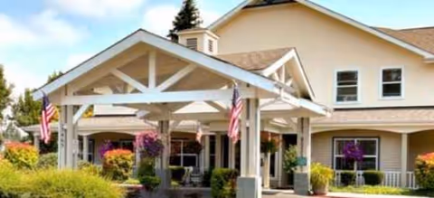 Brookdale Monroe senior living facility entrance with a white porte-cochere and hanging flower baskets.