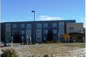 Exterior view of Commodore Park Plaza senior living building with a lawn.