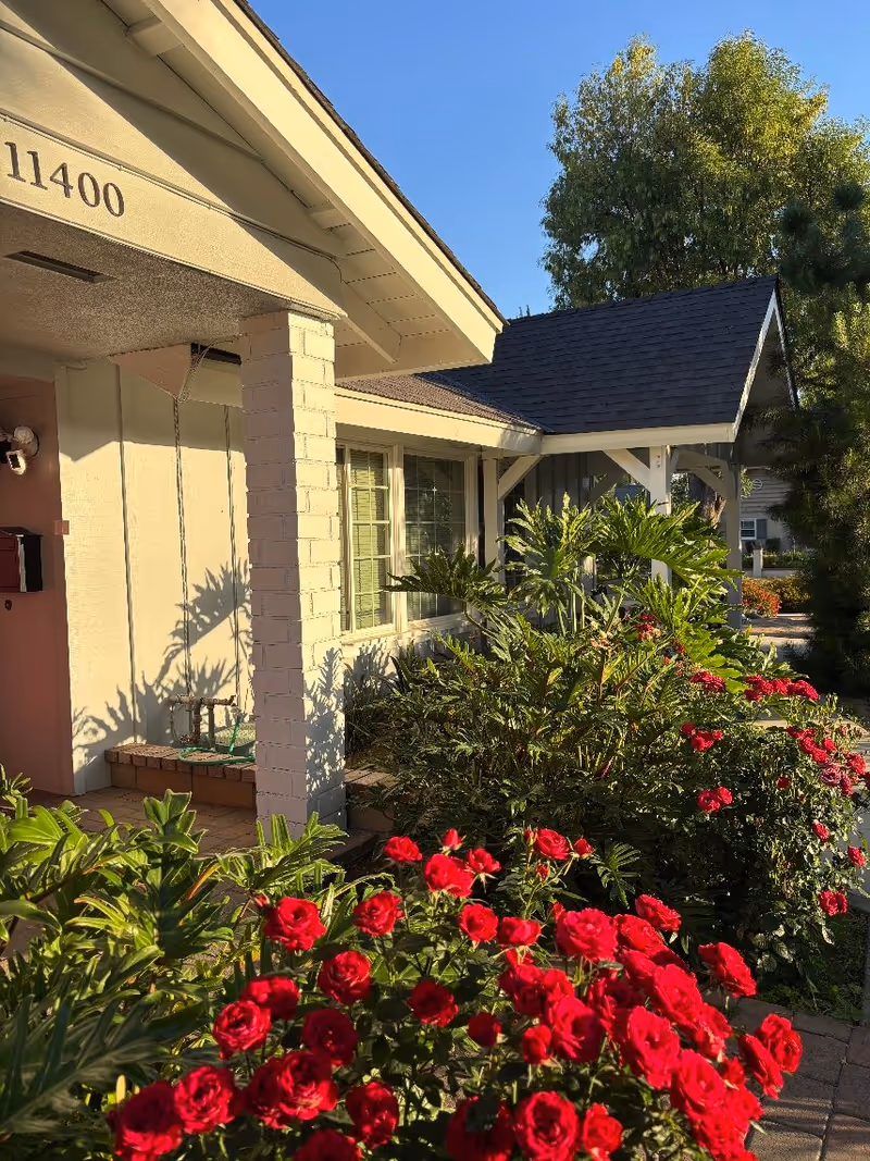 Front exterior of a single-story house with a porch, address number 11400, and red roses in the foreground.