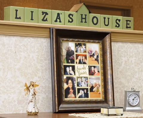 A mantle display with green blocks spelling "LIZASHOUSE", a framed photo collage, an angel figurine, a small clock and a book.