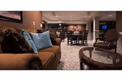 Cozy communal lounge with sofas, armchairs, and dining tables in a senior living facility.
