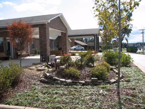 Exterior view of Sunshine Manor Retirement Home entrance with landscaped garden and walkway.