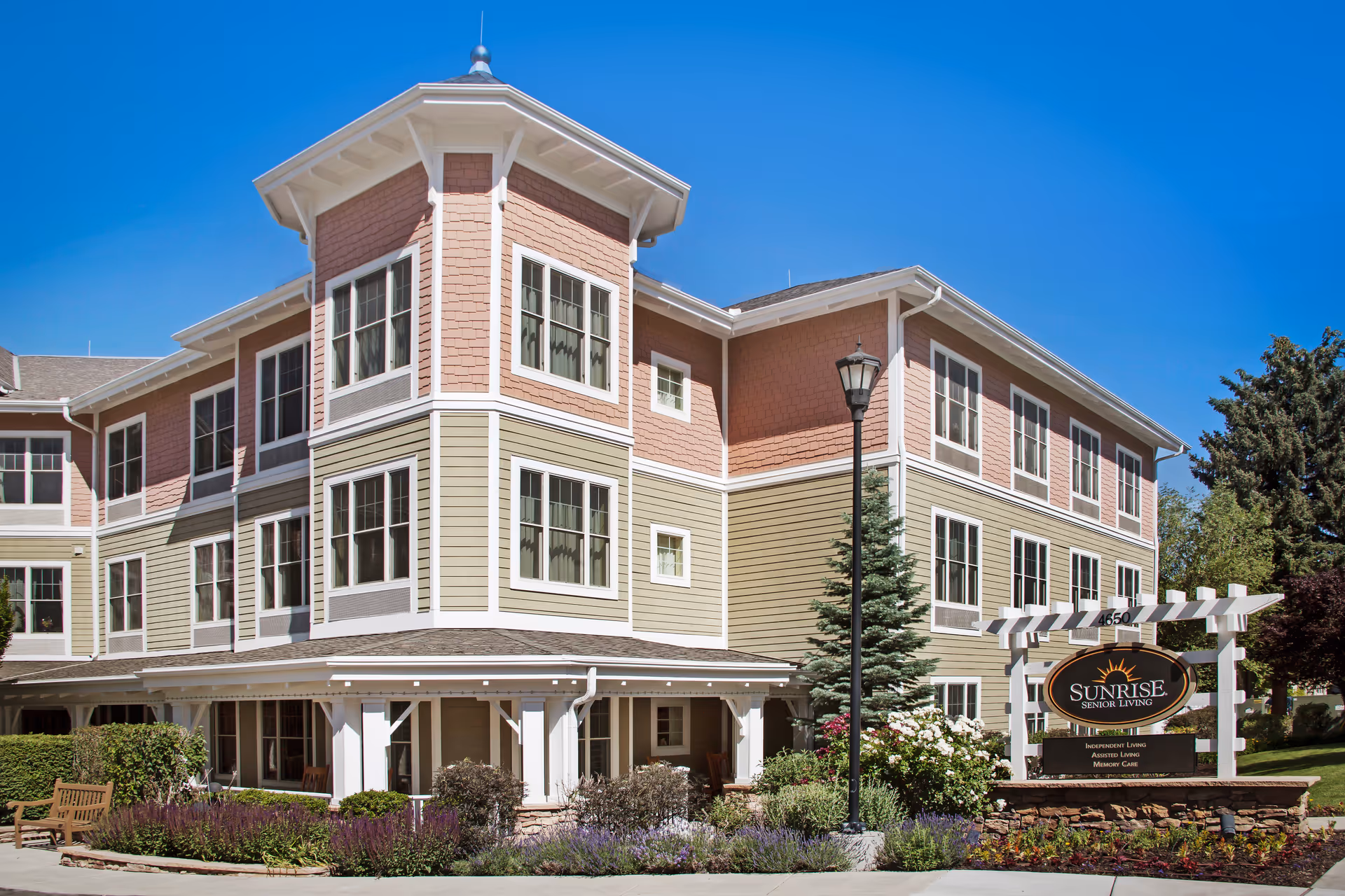 Front exterior of a three-story Sunrise Senior Living building with landscaping and an entrance sign.