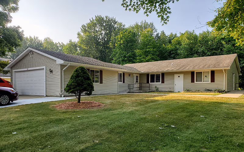 Exterior view of Innovative Housing Development Corporation building with a garage, green lawn, and trees.