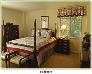 Sunlit bedroom with a four-poster bed dressed in floral bedding, matching dressers and a nightstand by a window.