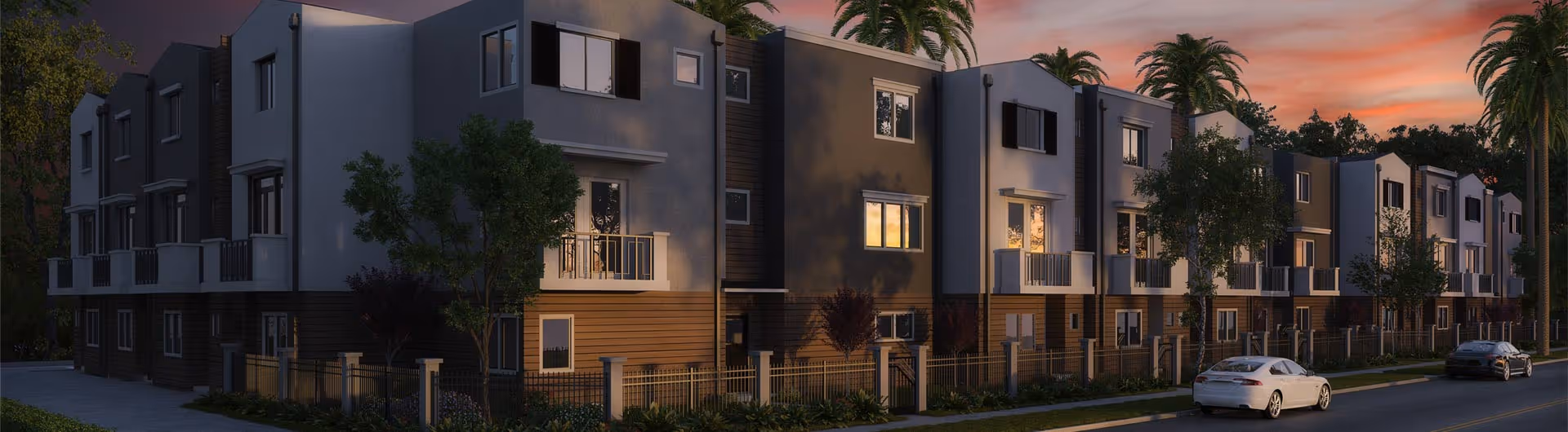 Exterior view of a modern multi-story residential building complex at sunset with trees and parked cars along the street.