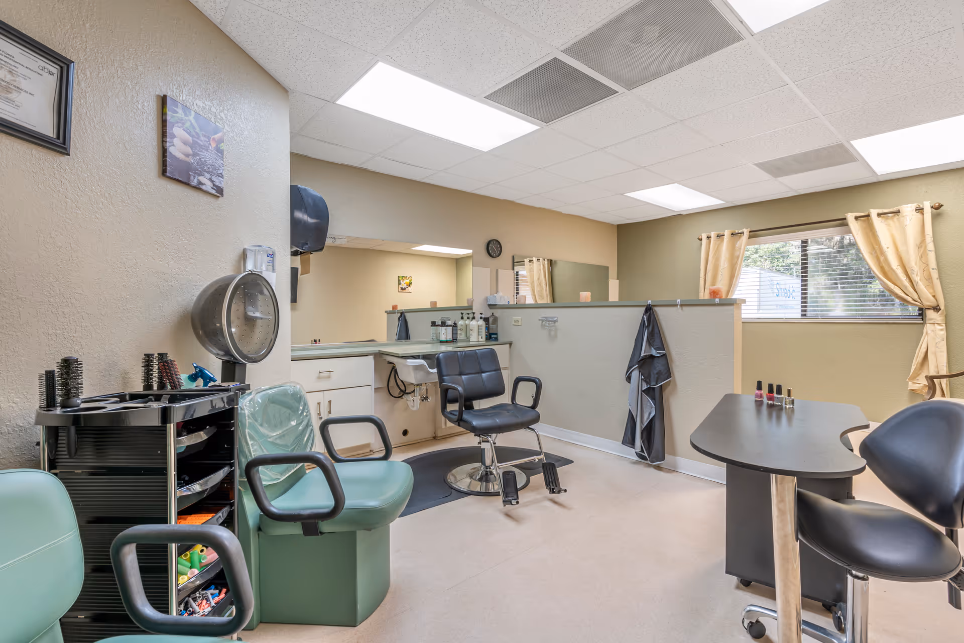 Interior salon area with hair styling chairs, a nail table, and salon equipment.