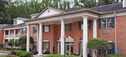 Brick senior living facility with white columns and a covered portico entrance.