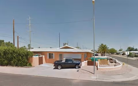 Exterior view of a single-story peach-colored care home with a pickup truck in the driveway.
