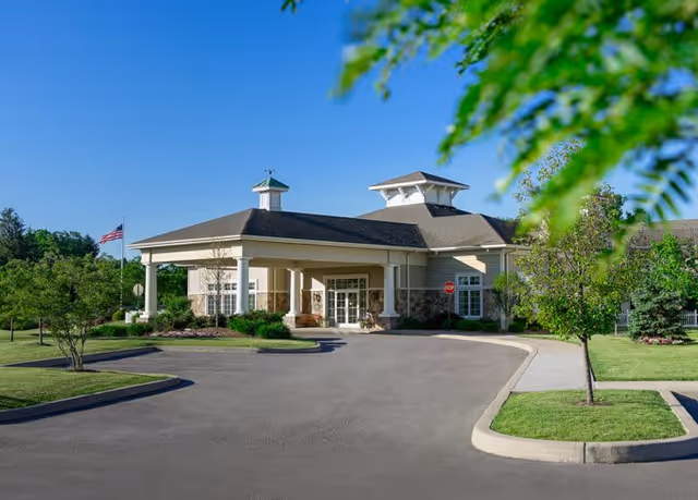 Exterior view of The Addison of Erie Station with a landscaped entrance, featuring a peaked roof and surrounding greenery.