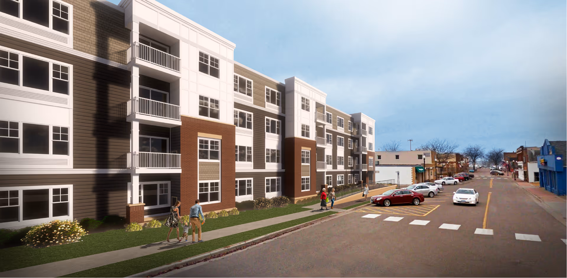 Street view of a modern multi-story residential building with balconies and large windows. People are walking on the sidewalk in front of the building. Several cars are parked along the street, and other buildings are visible further down the road under a clear sky.