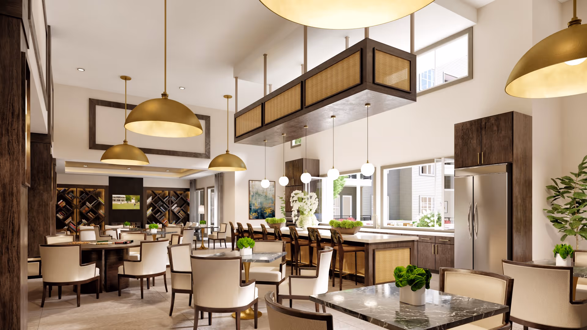 A spacious and modern common area with a kitchen and dining space. The room features multiple tables with beige upholstered chairs, a large kitchen island with bar stools, dark wood cabinetry, stainless steel refrigerator, and large windows letting in natural light. There are decorative plants on the tables and hanging pendant lights with gold finishes. In the background, there is a seating area with bookshelves and a TV mounted on the wall.