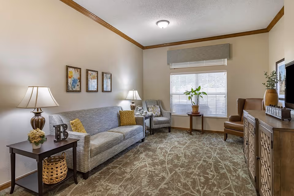 Well-lit living room with a gray sofa, armchairs, side tables, decorative accents and a TV cabinet.