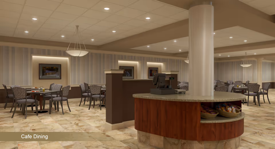 Spacious cafe-style dining room with multiple tables and chairs and a central host counter under soft ceiling lighting.