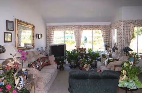 Cozy living room in a senior facility with sofas, plants, and large windows.
