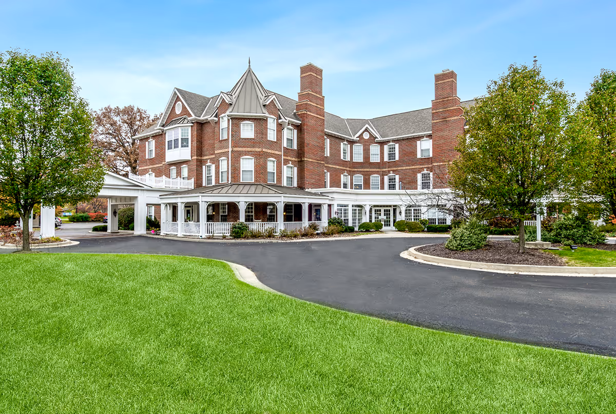 Brick multi-story senior living facility with a covered entrance, circular driveway and landscaped lawn.