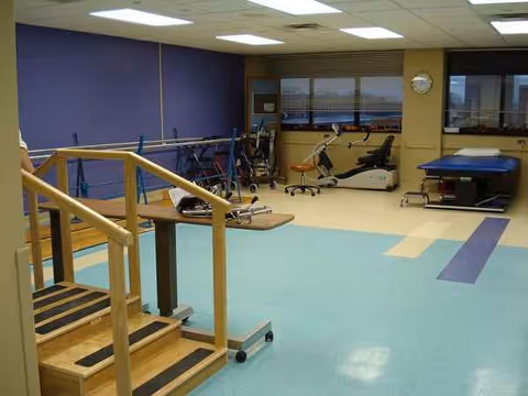 Interior therapy gym with parallel bars and exercise equipment in a senior facility.