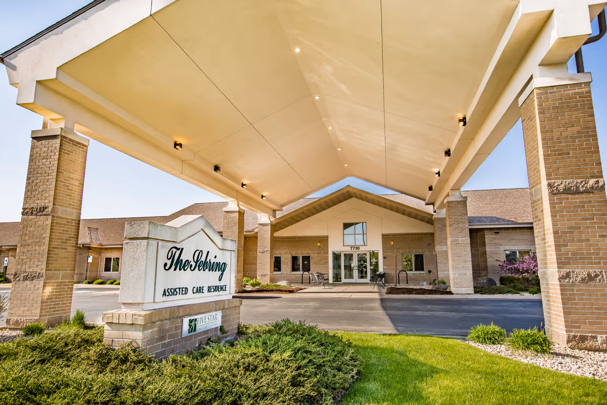 Front entrance of an assisted care residence with a covered porte-cochere and a sign reading 'The Sebring Assisted Care Residence'.