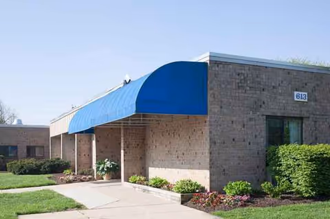 Exterior view of Hammonds Lane Center entrance with blue awning and brick facade.