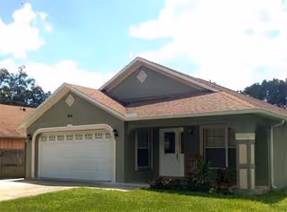 Front exterior of Bella Rose ALF house with garage and green lawn.