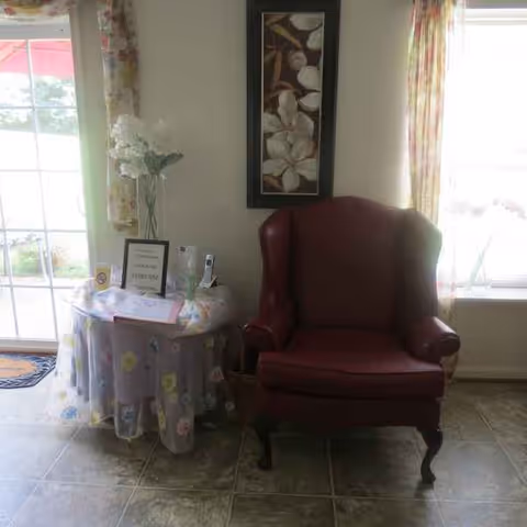 Red leather armchair beside a floral table, window, and wall art in a cozy living room.