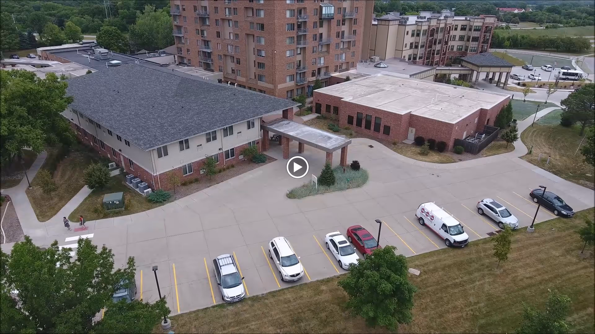 Aerial view of The Lindens at Green Hills facility showing multiple buildings, a parking lot with several cars, surrounding greenery, and pathways.