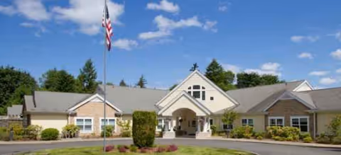 Single-story senior-living facility with a welcoming entrance, flagpole, and landscaped front yard.